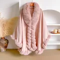 Detail of a light pink oversized knit poncho with plush faux rabbit fur trim on a hanger - Pink
