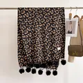 Détail d'une écharpe léopard avec franges à pompons noirs et étiquette tissée - 180x68cm / Chameau