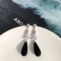 Dettaglio di orecchini pendenti in argento con pietre marquise e perle nere eleganti - Argento & Nero