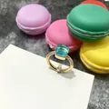 Anillo dorado con gema azul claro de corte cuadrado y detalles en tarjeta de papel - Talla 6 / Borde Dorado Azul Mar