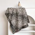 Detail of leopard print jacquard scarf with fringe edge on a minimalist bookshelf - 185x65cm / Black