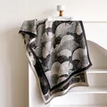 Detalle de chal pashmina con estampado de hojas de ginkgo y flecos en el soporte - 185x65cm / Negro