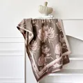 Dettaglio di sciarpa floreale vintage con trama morbida e frange su sfondo minimalista - 185x65cm / Cammello