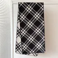 Detailed view of black and white plaid scarf with lockstitch edges and soft texture - Black