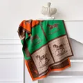 Detail van sjaal met paardenprint in levendig oranje en groen met fijne franjes - koffiekleur