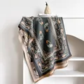 Nahaufnahme eines Paisley-Jacquard-Schals mit Quasten-Details in warmer Heim-Atmosphäre - Grau