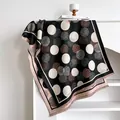 Close-up of geometric polka dot cashmere-like scarf with fringe details and woven texture - Black