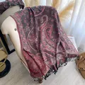 Dettaglio dei motivi paisley jacquard e nappine blu navy su una morbida stola invernale - Rosso Scuro