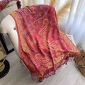 Dettaglio di uno scialle jacquard paisley con frange rosse su una poltrona elegante - Rosso