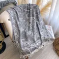 Detail of grey paisley jacquard shawl with soft fringes on an indoor armchair - Silver Gray