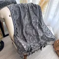 Châle rétro en jacquard paisley gris avec franges noires sur un fauteuil chic - Gris clair