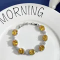 Macro shot of silver bracelet with oval yellow gemstones and zircon floral halo detailing - Yellow