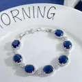 Macro detail of silver oval sapphire zirconia bracelet on a white ceramic plate - Dark Blue