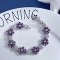 Detail of flower bracelet featuring purple and white cubic zirconia on a white plate - Purple