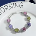 Detailed shot of halo-set oval pink, purple, and yellow gemstones on a silver bracelet - Gradient Multicolor