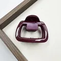 Dettaglio della clip per capelli rosso scuro lucido su vassoio in legno con denti - Stile Trapezio Cavo (Stile Quattro)