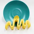 Dettaglio macro di un fermaglio per capelli ondulato giallo su sfondo di pietra - Giallo
