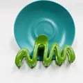 Dettaglio di un fermaglio per capelli ondulato verde brillante con finitura lucida - Verde