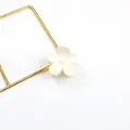 Matte white flower mini hair claw clip for women on a gold display stand - Off White