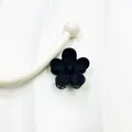 Matte black small five-petal flower hair claw clip shown on a white textured background - Black