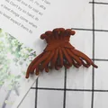 Matte terracotta hair claw clip with woven design on white textured background - Brick Red