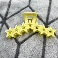 Vibrant yellow star-shaped hair claw clip with hollow design on grey textured background - Yellow