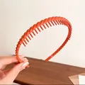 Cerchietto arancione brillante con dentini antiscivolo, mostrato tenuto in mano - Arancione Intrecciato