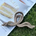 Matte light coffee acrylic hair claw clip with large wavy twisted design on grass - Khaki