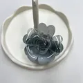 Pinza per capelli a fiore grigio traslucido con petali a forma di cuore su piatto bianco - Sfumatura Nera