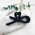 Pinza per capelli a fiocco nero opaco tenuta in mano mostra texture vintage e misura - Nero