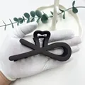 Dettaglio della pinza per capelli geometrica nero opaco con finitura satinata e design a croce - grigio scuro