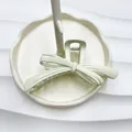 Elegant mint green matte bow hair claw clip displayed on a cream jewelry tray - Rubber Paint White