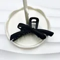 Matte black bow hair claw clip for thick hair displayed on a white ceramic tray - Rubber Paint Black