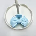 Pince à cheveux noeud bleu clair finition brillante sur un plateau décoratif blanc - Nœud Bleu Ciel