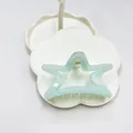 Light blue star-shaped hollow hair claw clip with a glossy finish on white floral tray - Approximately 24.4g Of Transparent Green Five-pointed Star