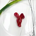 Mini red bow-shaped hair claw clip made of glossy acrylic on a white decorative plate - Bowtie