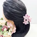 Vista dettagliata di una pinza per capelli con fiori rosa sfumati su capelli castani - Pesca