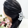 Détail d'une pince à cheveux double fleur en acétate marbré gris sur cheveux foncés - Gris