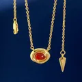 Golden necklace with oval red gemstone pendant and geometric tag on deep blue background - Gold Red Agate Necklace