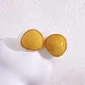 Minimalistische gelbe dreieckige Ohrstecker mit Goldrand auf einer Dekovolke - Goldfarbe (Gelber Chalzedon)