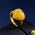 Gros plan d'une ambre ovale sur anneau doré sur une surface de boîte à bijoux bleue - Taille 8 / Or + Calcédoine Jaune