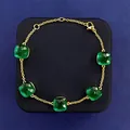 Detail of green emerald-cut crystal stones on a gold chain bracelet with lobster clasp - Gold + Peacock Blue
