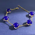 Golden bracelet with five deep blue square gemstones and lobster clasp on dark background - Gold (Lapis Blue + Clear)