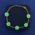 Elegant gold bracelet featuring five square green crystals on a navy blue display box - Gold And Jade Green