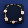 Elegant gold bracelet featuring five square pink crystal gemstones on a navy blue background - Gold Tone + Pink Jade