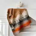 Artistic abstract print winter scarf with tassels displayed on a minimal white table - Khaki