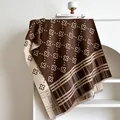 Dettaglio scialle in maglia double-face con motivi a quadrifoglio e morbide nappe marroni - Marrone