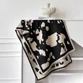 Detailweergave van zwart-witte kasjmier sjaal met koeprint en franje aan de randen op de plank - 185x65cm / Zwart
