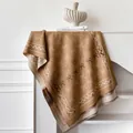 Bruine gebreide sjaal met strikpatronen en franjes op een minimalistische witte schouw - Grote Portie / Khaki