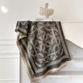 Dettaglio macro di sciarpa in cashmere grigio scuro con bordi a greca e motivi barocchi - Grigio